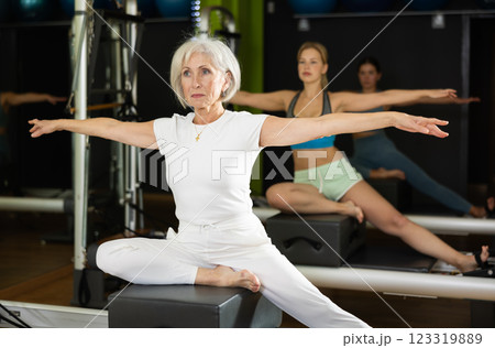 Gray-haired woman sitting on a Pilates platform Gray-haired woman sitting on a Pilates platform 123319889