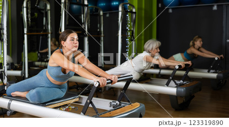 Woman in a sportswear holds the handles of the reformer Woman in a sportswear holds the handles of the reformer 123319890