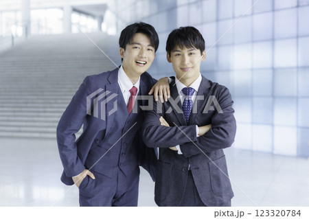 オフィスビルの階段の前に立つ仲の良い若いビジネスマン2人のポートレート 123320784