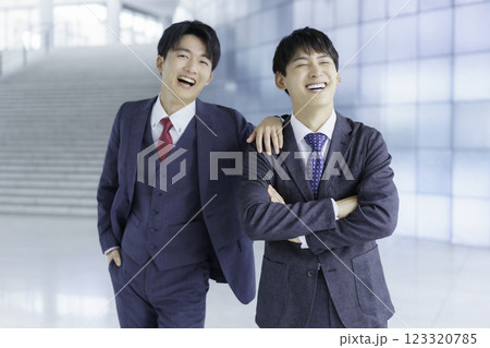 オフィスビルの階段の前に立つ仲の良い若いビジネスマン2人のポートレート 123320785