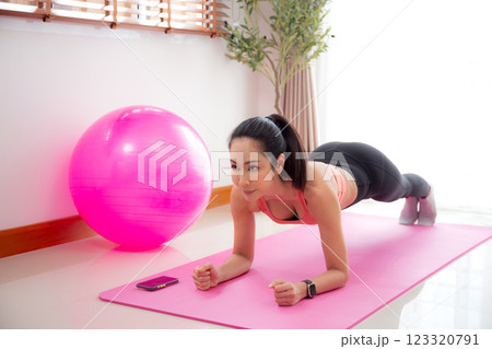 Young asian woman practice workout with posing plank on mat while motivation and determined. Young asian woman practice workout with posing plank on mat while motivation and determined. 123320791