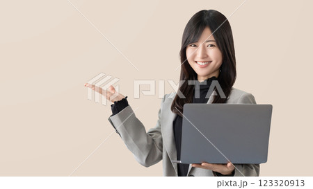 ノートパソコンを持って案内をする笑顔の女性・ビジネスウーマン 123320913