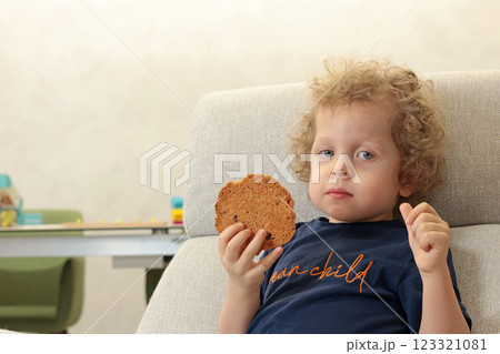 Little boy 3 years old in chair watching cartoon in room and eating biscuits. Children and lifestyle. Emotional Intelligence. Little boy 3 years old in chair watching cartoon in room and eating biscuits. Children and lifestyle. Emotional Intelligence. 123321081