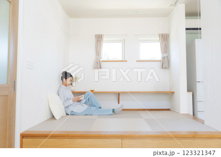 畳の小上がりでくつろぐ女性 畳の小上がりでくつろぐ女性 123321347