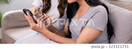 Two friends browsing and discussing shopping options on a mobile phone together 123321731