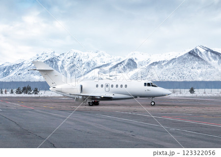 Taxiing of white luxury business jet on airport in winter on the background of high scenic snow capped mountains Taxiing of white luxury business jet on airport in winter on the background of high scenic snow capped mountains 123322056