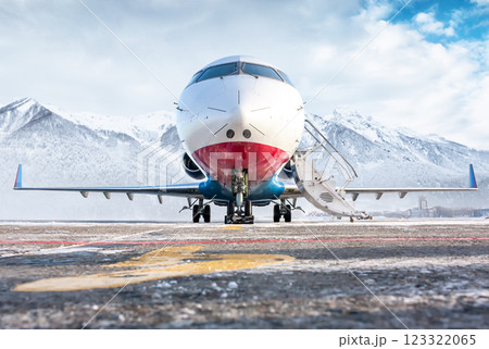 Front view of the modern luxury corporate business jet with open gangway door on the winter airport apron on the background of high scenic mountains Front view of the modern luxury corporate business jet with open gangway door on the winter airport apron on the background of high scenic mountains 123322065