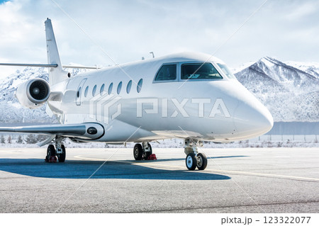 White luxury business jet on airport apron in winter on the background of high scenic snow capped mountains 123322077