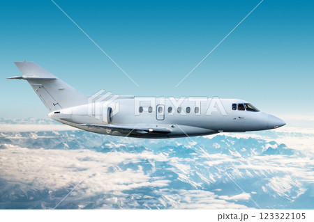 White modern corporate aircraft flies over snow-covered mountains 123322105