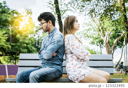 Upset young couple sitting back to back in a park, unhappy couple sitting back to back on bench. Concept of couple problems and crisis. Young couple arguing sitting back to back on a bench Upset young couple sitting back to back in a park, unhappy couple sitting back to back on bench. Concept of couple problems and crisis. Young couple arguing sitting back to back on a bench 123323495