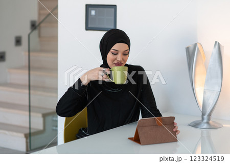 Modern Muslim woman in a hijab working on a tablet at home. 123324519