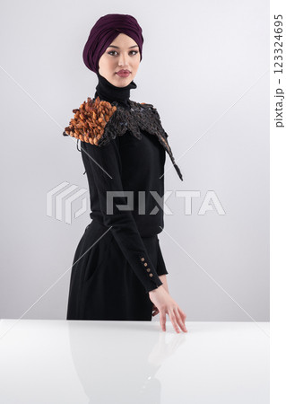 A stylish Muslim woman in a hijab presents her innovative handmade fashion accessory crafted from dried plums in a professional studio. 123324695