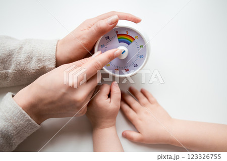 Female adult and child interaction with kitchen timer on white surface 123326755