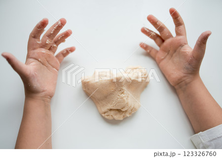 Child hands playing with soft dough on white background 123326760