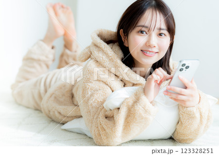 部屋でスマホを操作する若い女性 123328251