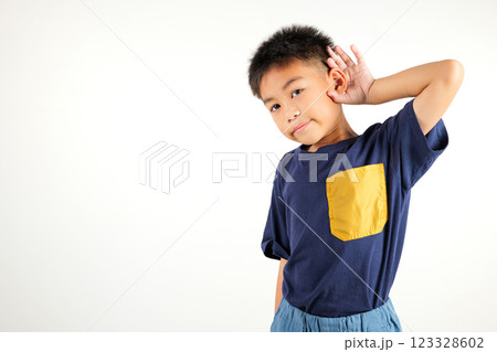 Portrait Asian young child smiling overhearing listening sound to gossip with attention with hand on ear studio shot isolated on white background with copy space hearing gesture, primary kid boy 123328602
