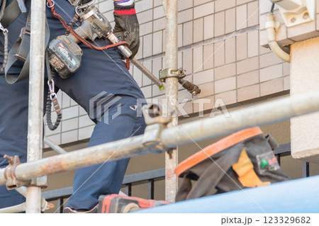 【マンション大規模修繕工事　壁つなぎを接続し足場を作る作業員】 123329682