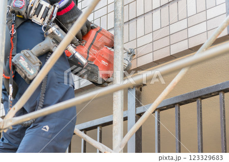 【マンション大規模修繕工事　足場を作る作業員ドリル】 123329683