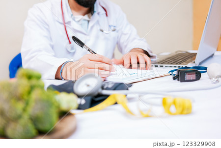 Close-up of nutritionist writing on notepad. Hands of male nutritionist taking notes at his desk, Nutritionist hands taking medical records in the office 123329908