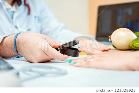 Hand of nutritionist using oximeter on finger of female patient. Close up of hands of nutritionist using pulse oximeter on patient finger.  Nutritionist measuring oxygen pulse to patient 123329925