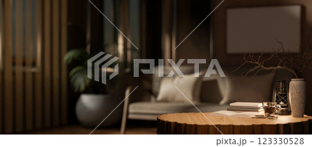 The round wooden table with decors in the middle, with blurry background of dark living room. 123330528
