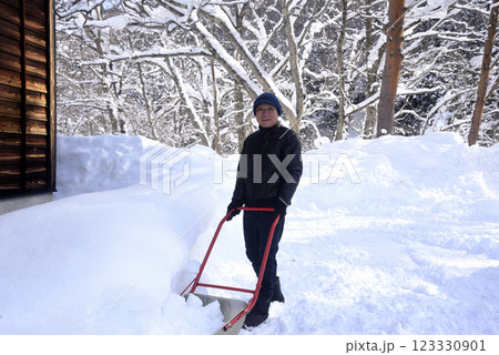 雪国でスノーダンプを使用して除雪をしている老人 123330901