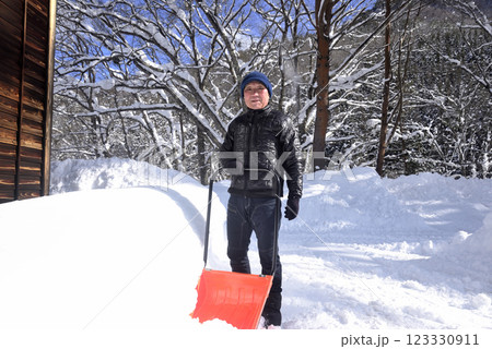 雪国でスノーダンプを使用して除雪をしている老人 123330911
