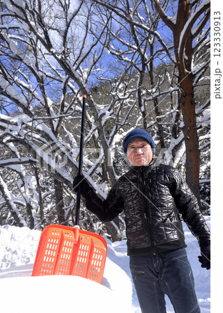 雪国で雪はねを使用して除雪をしている笑顔の老人 123330913