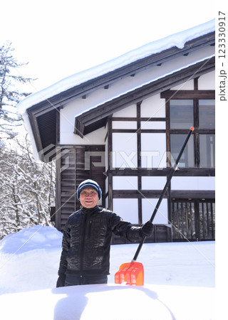 雪国で雪はねを使用して除雪をしている笑顔の老人 雪国で雪はねを使用して除雪をしている笑顔の老人 123330917