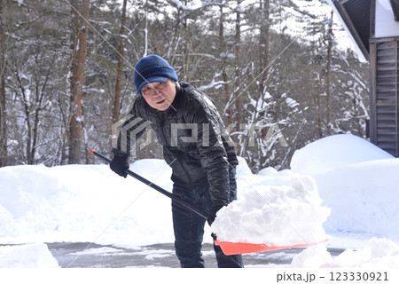 雪国で雪はねを使用して除雪をしている笑顔の老人 雪国で雪はねを使用して除雪をしている笑顔の老人 123330921