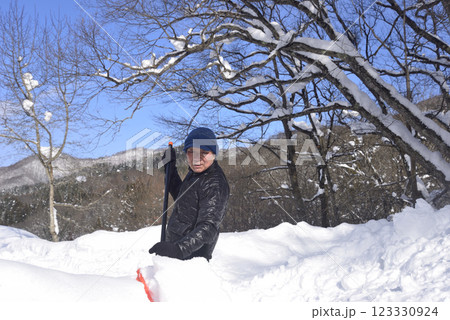 雪国で雪はねを使用して除雪をしている笑顔の老人 123330924