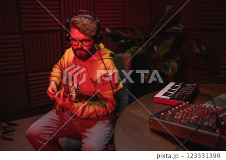 Man vocal artist singing in a recording studio with guitar copy space. Male singer singing a song and playing guitar. Sound record and music streaming concept Man vocal artist singing in a recording studio with guitar copy space. Male singer singing a song and playing guitar. Sound record and music streaming concept 123331399