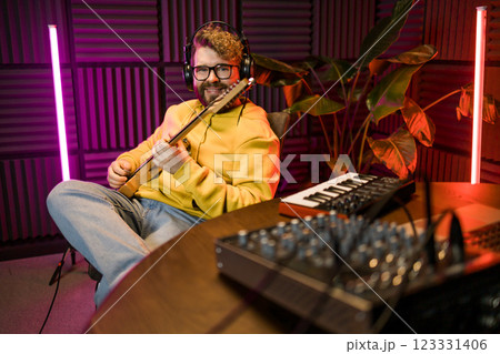 Man vocal artist singing in a recording studio with guitar. Male singer singing a song and playing guitar. Sound record and music streaming concept Man vocal artist singing in a recording studio with guitar. Male singer singing a song and playing guitar. Sound record and music streaming concept 123331406