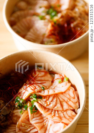 Donburi with sliced salmon on sushi rice in paper container. Healthy take away food. 123331516