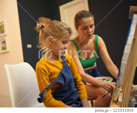 Teacher in workshop teched two girls how to assemble a thermo mosaic  123331954