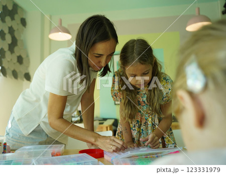 Teacher in workshop teched two girls how to assemble a thermo mosaic  123331979