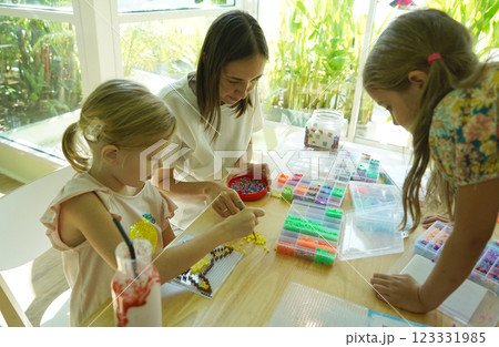 Teacher in workshop teched two girls how to assemble a thermo mosaic  123331985