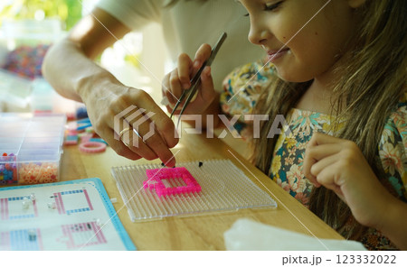 Teacher in workshop teched two girls how to assemble a thermo mosaic  123332022