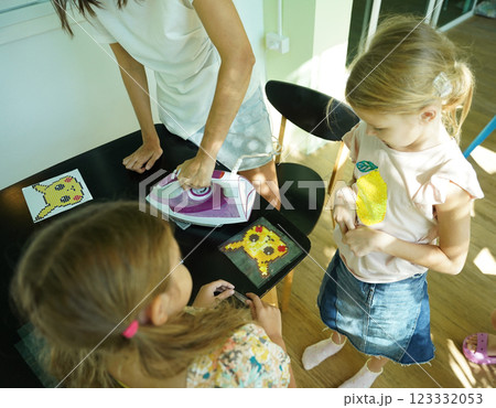 Teacher in workshop teched two girls how to assemble a thermo mosaic  123332053