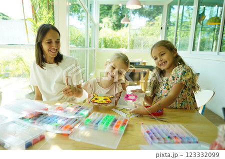 Teacher in workshop teched two girls how to assemble a thermo mosaic  123332099