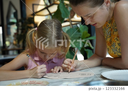 A young mother and her daughter enjoy a creative art session at home  123332166
