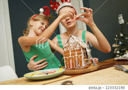 Mother and daughter at the table cooking gingerbread house for Christmas Mother and daughter at the table cooking gingerbread house for Christmas 123332190
