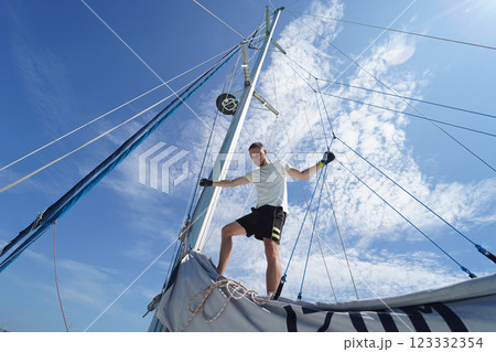 Male captain stands proudly on a sailboat enjoying the moment Male captain stands proudly on a sailboat enjoying the moment 123332354