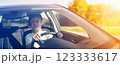 Young woman sitting behind the wheel and driving a car on a sunny day. 123333617
