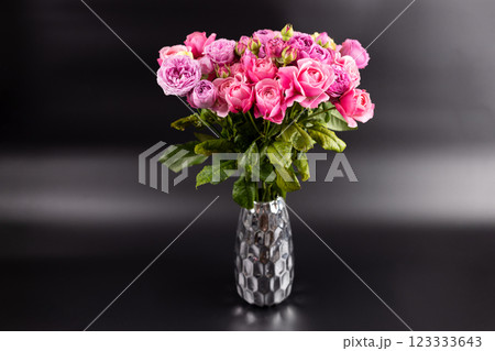 on black background with iridescent light there is a figured iron vase with a large bouquet of pink peony roses a gift for a beloved woman a favorite color home decoration first date March 8th 123333643