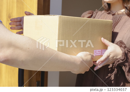 玄関先で荷物を受け取る女性と配送スタッフ 123334037