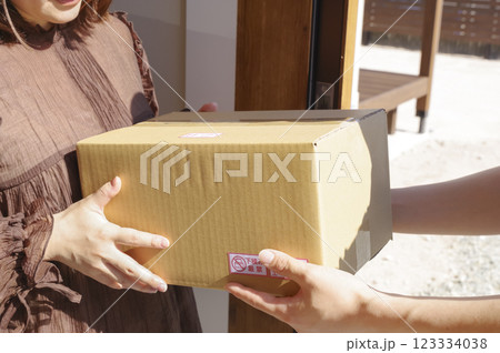 玄関先で荷物を受け取る女性と配送スタッフ 玄関先で荷物を受け取る女性と配送スタッフ 123334038