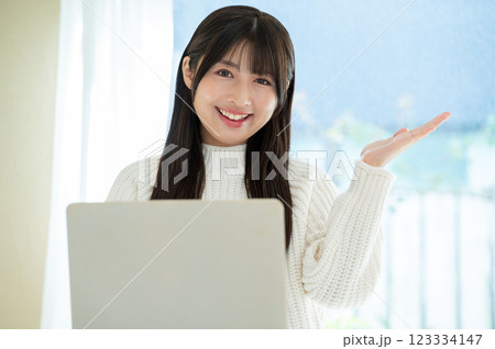 パソコンの前でご案内をする若い女性 123334147