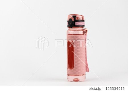 close-up on white background stands plastic pink rubberized drinking sports bottle with hand strap daytime water control locking lid close-up on white background stands plastic pink rubberized drinking sports bottle with hand strap daytime water control locking lid 123334913