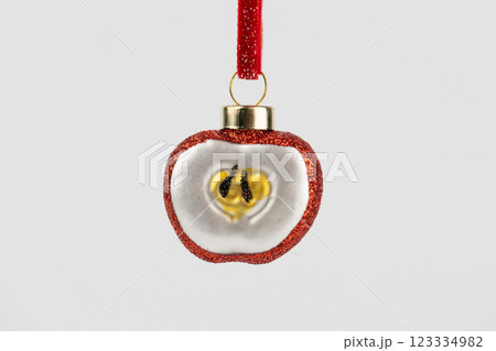close up on white background, a hanging Christmas tree toy in the shape of a fruit, an apple, on a red rope, glass New Year's toys, modern decor, enameled toys with sparkles close up on white background, a hanging Christmas tree toy in the shape of a fruit, an apple, on a red rope, glass New Year's toys, modern decor, enameled toys with sparkles 123334982